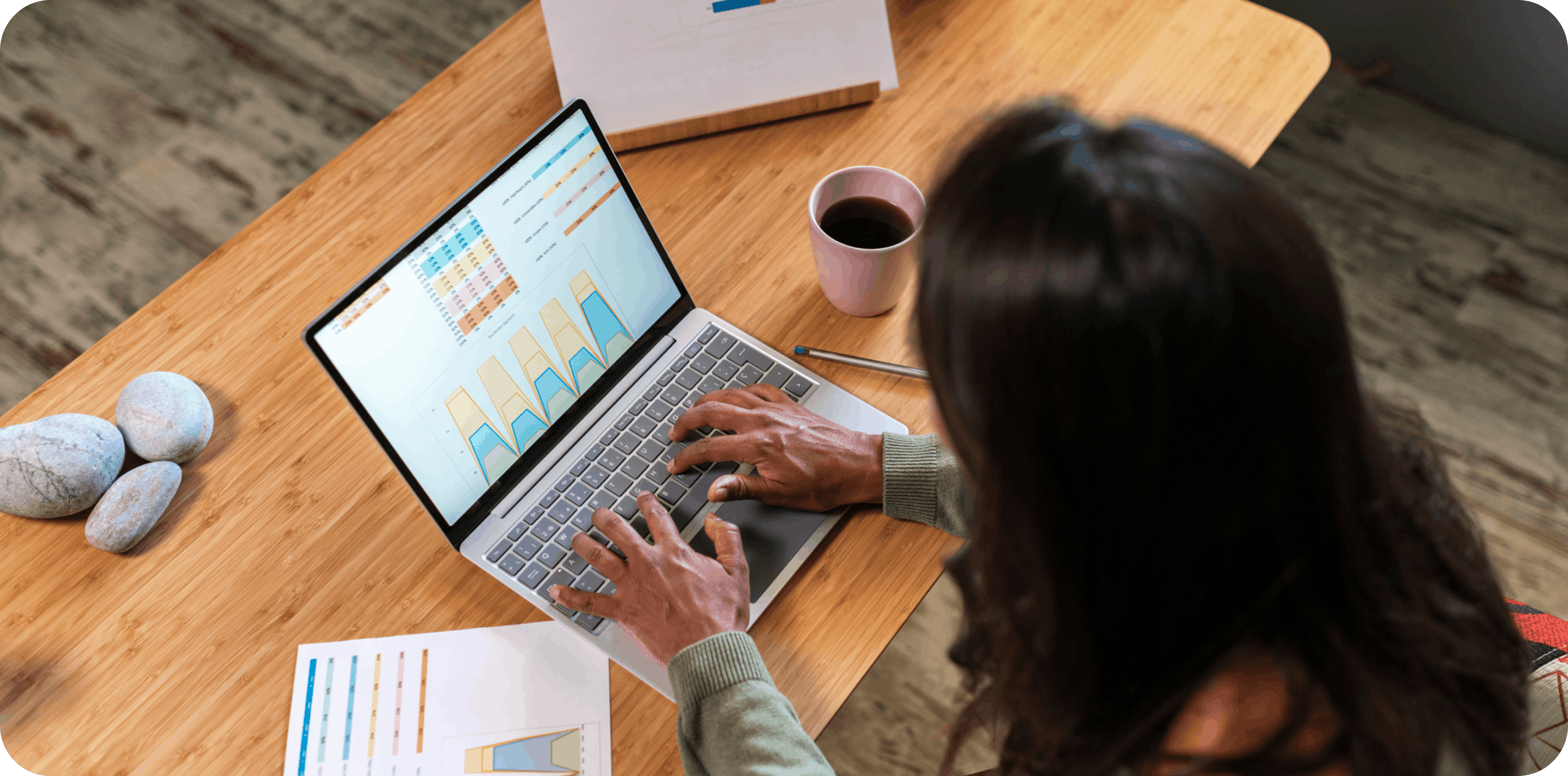 A person sitting at a desk with their laptop and a cuo of coffee